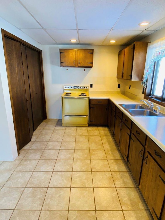 kitchen with sink, a drop ceiling, light tile patterned floors, and range with electric stovetop