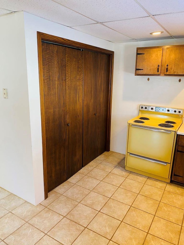 kitchen with a drop ceiling, light tile patterned flooring, and stove