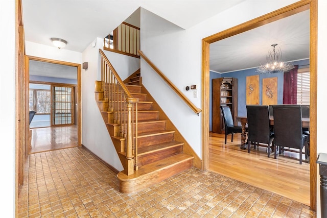 stairway with a notable chandelier, crown molding, and hardwood / wood-style flooring