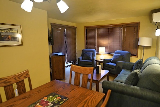 living room with a wall unit AC and ceiling fan