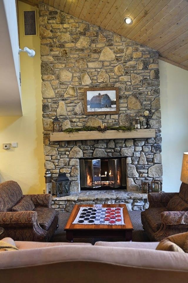 living room featuring lofted ceiling, wooden ceiling, and a stone fireplace