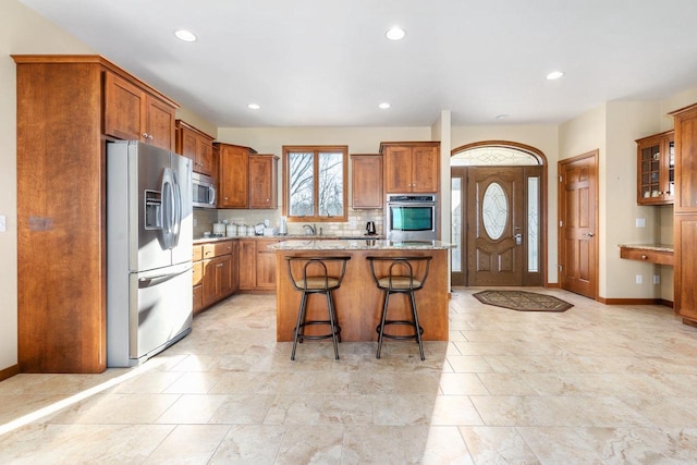 kitchen with light stone counters, stainless steel appliances, a breakfast bar, a kitchen island, and backsplash