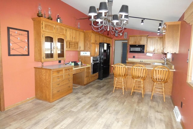 kitchen with vaulted ceiling, light wood-type flooring, kitchen peninsula, a chandelier, and black appliances