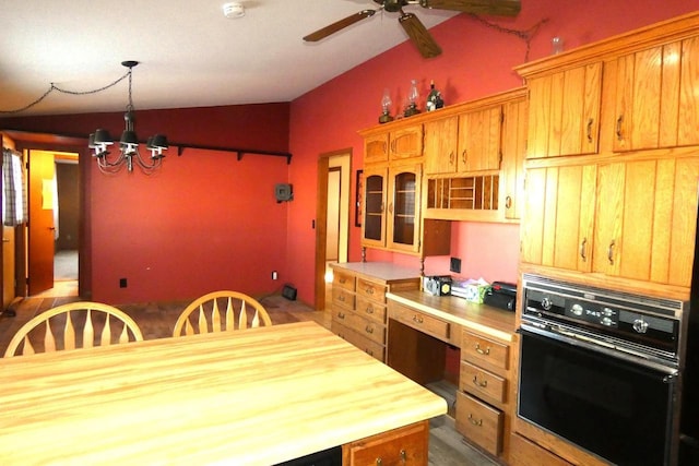 kitchen with vaulted ceiling, hanging light fixtures, oven, wooden counters, and ceiling fan with notable chandelier