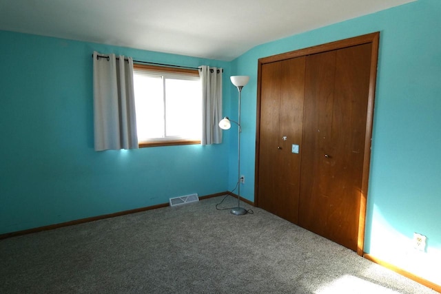 unfurnished bedroom featuring vaulted ceiling, a closet, and carpet