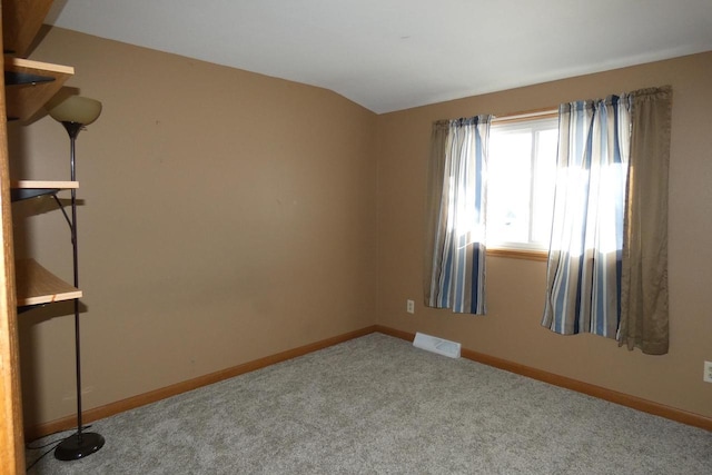 carpeted spare room featuring vaulted ceiling