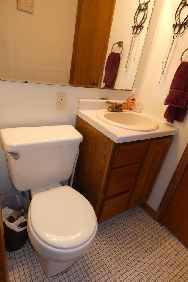 bathroom with toilet, vanity, and tile patterned flooring