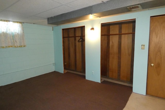 unfurnished bedroom featuring multiple closets and a drop ceiling