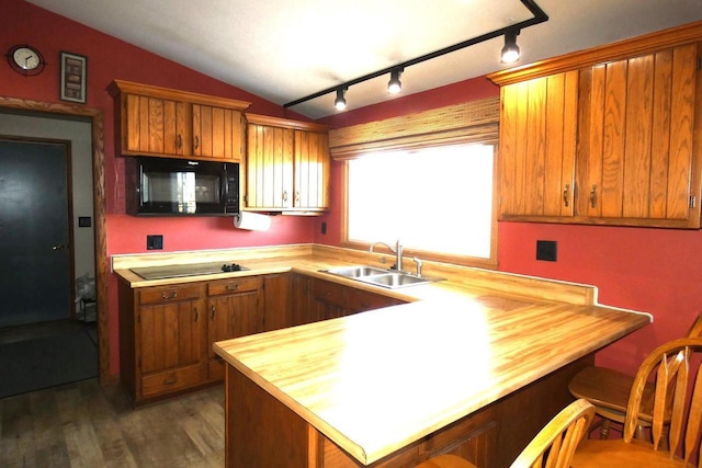 kitchen featuring sink, vaulted ceiling, kitchen peninsula, black appliances, and dark wood-type flooring