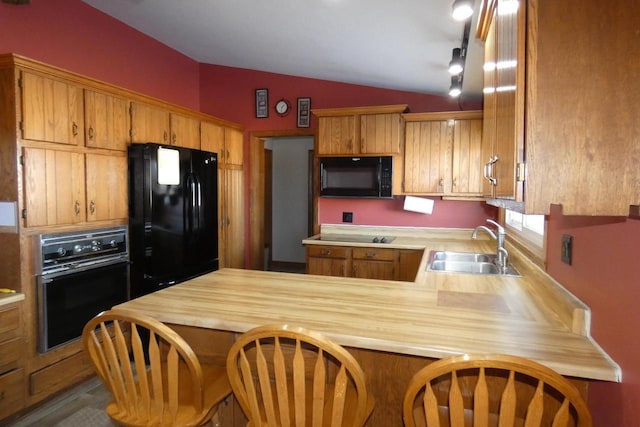 kitchen featuring a kitchen breakfast bar, black appliances, kitchen peninsula, sink, and lofted ceiling