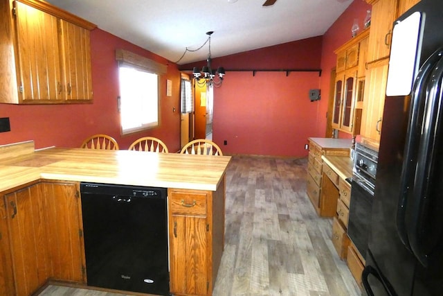 kitchen with black appliances, a notable chandelier, vaulted ceiling, and light wood-type flooring