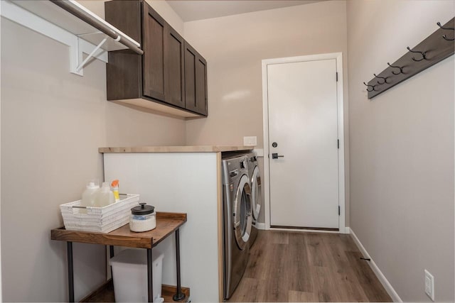 laundry room with washing machine and clothes dryer, cabinets, and light hardwood / wood-style flooring