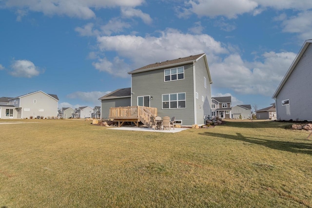 rear view of property featuring a deck, a yard, and a patio area