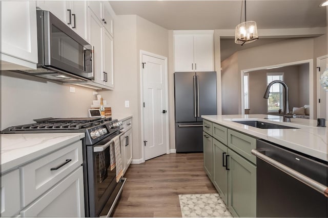 kitchen featuring decorative light fixtures, green cabinetry, white cabinetry, appliances with stainless steel finishes, and sink