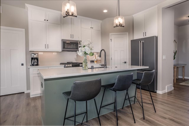 kitchen featuring an island with sink, appliances with stainless steel finishes, and white cabinetry