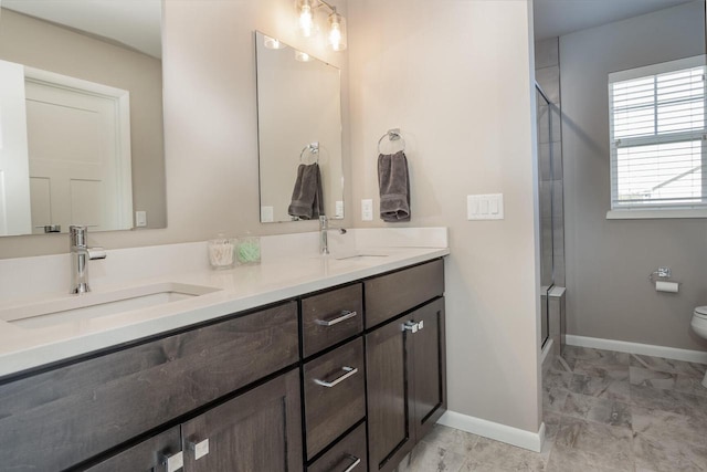 bathroom featuring toilet, vanity, and a shower with shower door