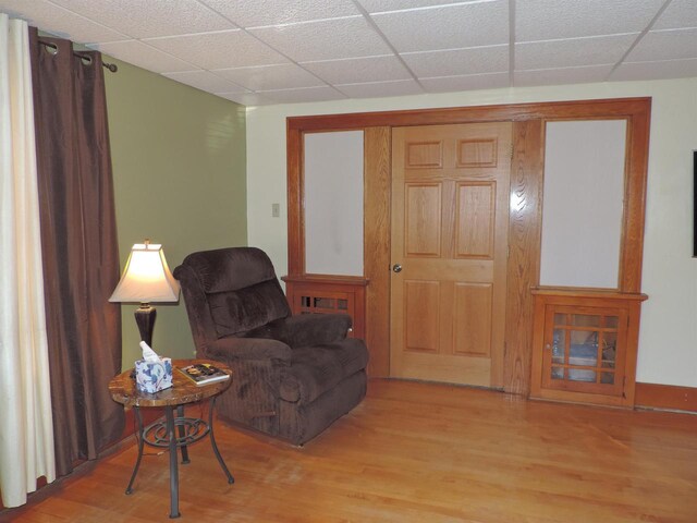 sitting room with light wood-type flooring and a paneled ceiling