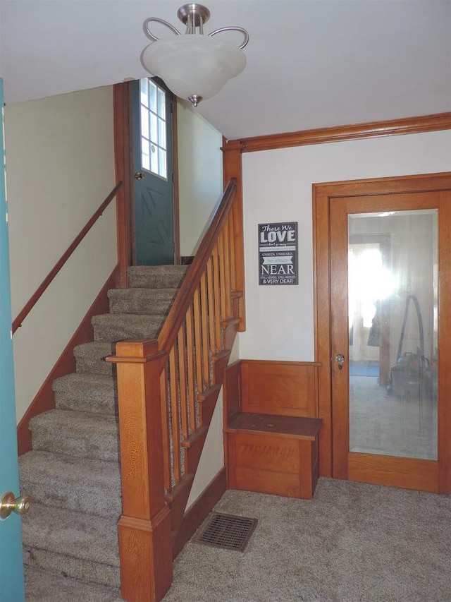 staircase featuring crown molding and carpet flooring