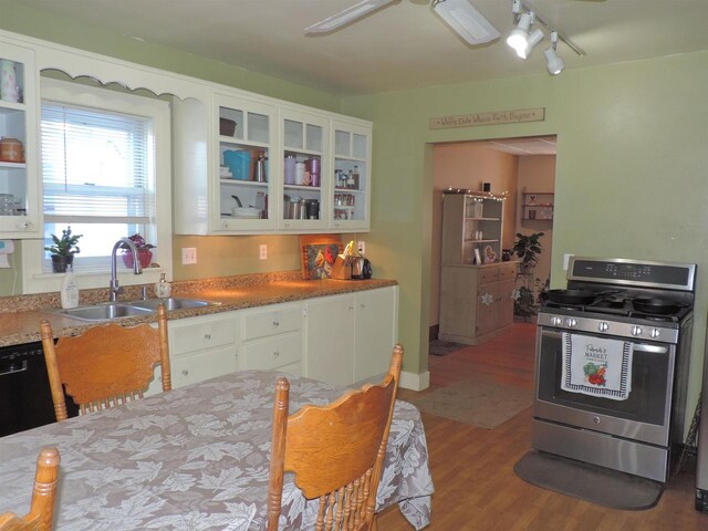 kitchen with gas stove, hardwood / wood-style floors, white cabinetry, black dishwasher, and sink