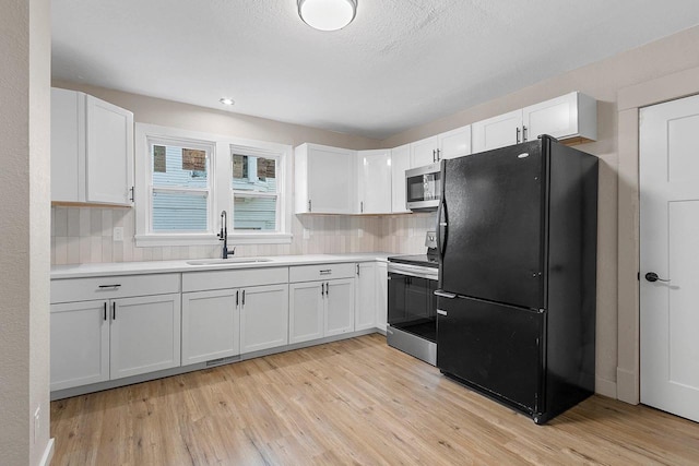 kitchen featuring appliances with stainless steel finishes, white cabinetry, backsplash, and sink