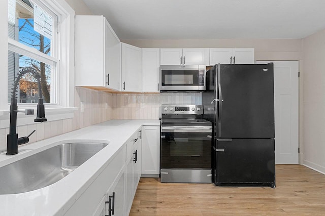 kitchen featuring white cabinets, appliances with stainless steel finishes, light hardwood / wood-style flooring, and sink