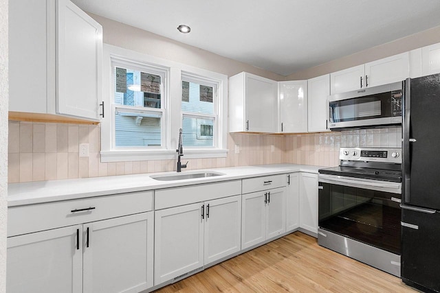 kitchen with sink, decorative backsplash, white cabinetry, and appliances with stainless steel finishes