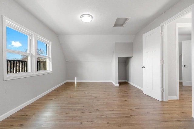 additional living space featuring light wood-type flooring and vaulted ceiling