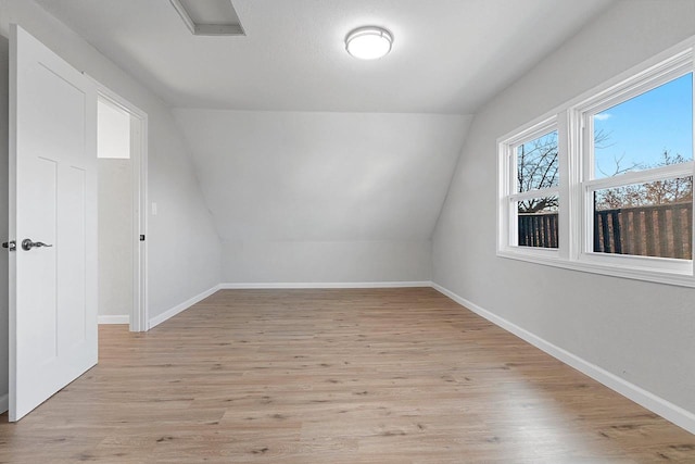 additional living space featuring light wood-type flooring and vaulted ceiling