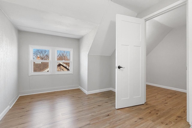 bonus room with light wood-type flooring and vaulted ceiling