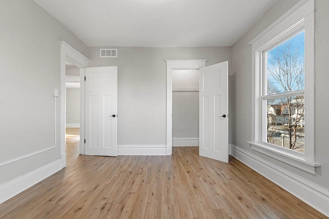 unfurnished bedroom featuring a closet, light hardwood / wood-style flooring, and multiple windows