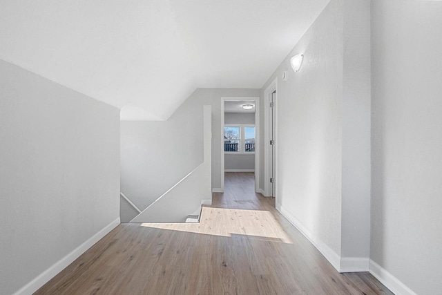 hallway with light hardwood / wood-style flooring and vaulted ceiling