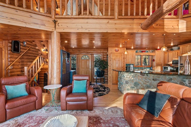 living room with a high ceiling, light hardwood / wood-style flooring, and rustic walls