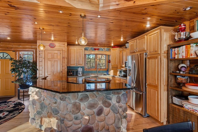 kitchen featuring light wood-type flooring, appliances with stainless steel finishes, pendant lighting, and a breakfast bar area