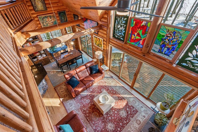 living room featuring a wealth of natural light, hardwood / wood-style floors, log walls, and high vaulted ceiling