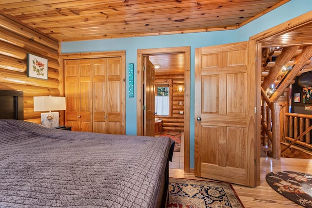 bedroom featuring log walls, a closet, light hardwood / wood-style floors, and wooden ceiling