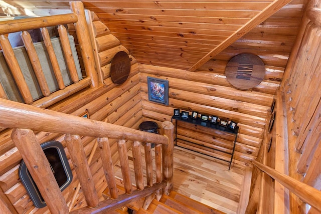 staircase featuring hardwood / wood-style floors, wooden ceiling, and log walls