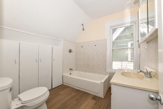 bathroom featuring toilet, hardwood / wood-style flooring, lofted ceiling, tile walls, and vanity