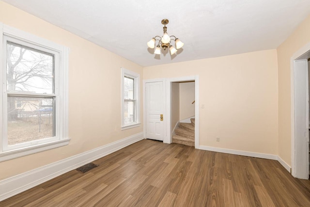 unfurnished room featuring an inviting chandelier and hardwood / wood-style floors