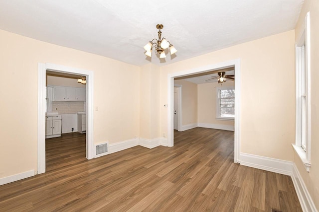 spare room with hardwood / wood-style floors and ceiling fan with notable chandelier