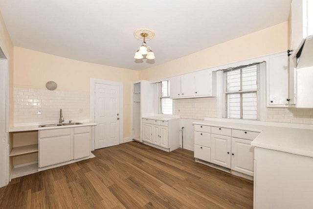 kitchen with sink, white cabinets, hardwood / wood-style floors, decorative backsplash, and pendant lighting