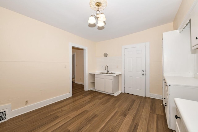 unfurnished dining area featuring dark wood-type flooring, an inviting chandelier, and sink