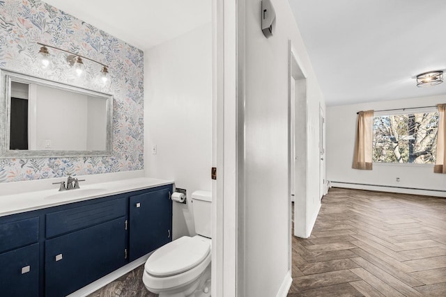 bathroom with vanity, toilet, parquet floors, and a baseboard heating unit