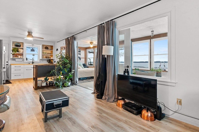 living room featuring ceiling fan, light hardwood / wood-style floors, and sink