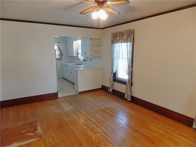 spare room featuring ceiling fan, light wood-type flooring, crown molding, and sink