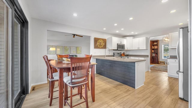 kitchen featuring appliances with stainless steel finishes, light hardwood / wood-style floors, ceiling fan, sink, and white cabinetry