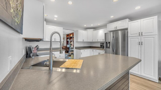 kitchen featuring sink, light hardwood / wood-style flooring, stainless steel refrigerator with ice dispenser, and white cabinetry