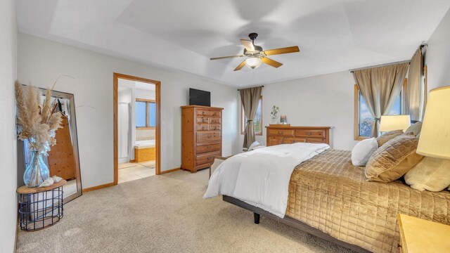 carpeted bedroom featuring ceiling fan, connected bathroom, and a raised ceiling