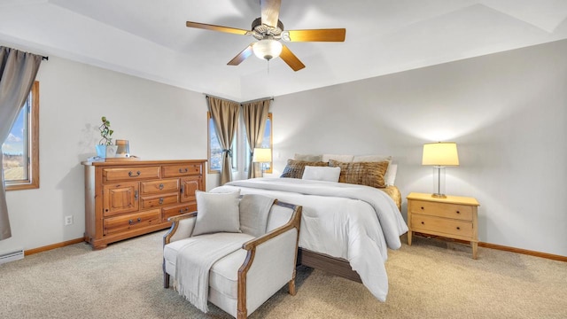 bedroom featuring light colored carpet, ceiling fan, a tray ceiling, and multiple windows