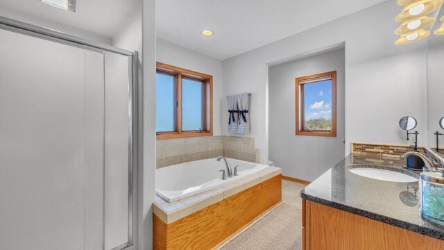 bathroom featuring tile patterned flooring, tiled bath, and vanity