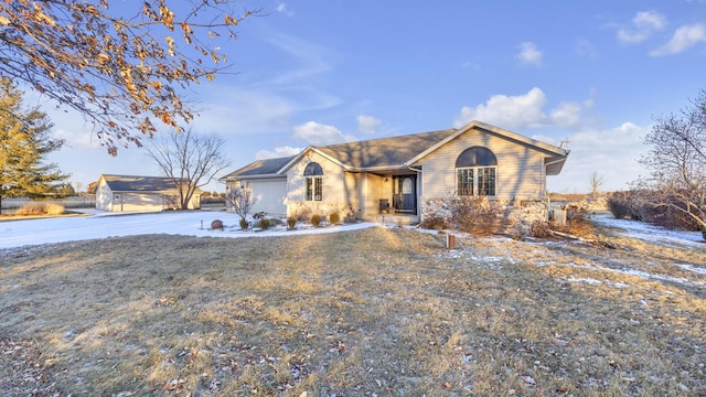 ranch-style home featuring a front yard, a garage, and an outbuilding